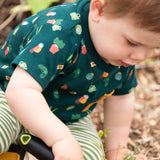 Child wearing the Little Green Radicals Spring garden organic cotton playset outfit. Repeat pattern green t-shirt and green and cream striped joggers. 
