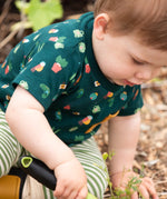 Child wearing the Little Green Radicals Spring garden organic cotton playset outfit. Repeat pattern green t-shirt and green and cream striped joggers. 