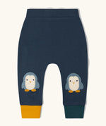 Little Green Radicals organic cotton penguin knee patch joggers with one yellow and one dark green leg cuff.