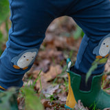 Close up of a child wearing the Little Green Radicals organic cotton knee patch joggers with a blue penguin design.
