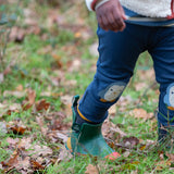 Child wearing the Little Green Radicals organic cotton knee patch joggers with a blue penguin design.
