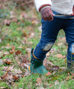 Child wearing the Little Green Radicals organic cotton knee patch joggers with a blue penguin design.