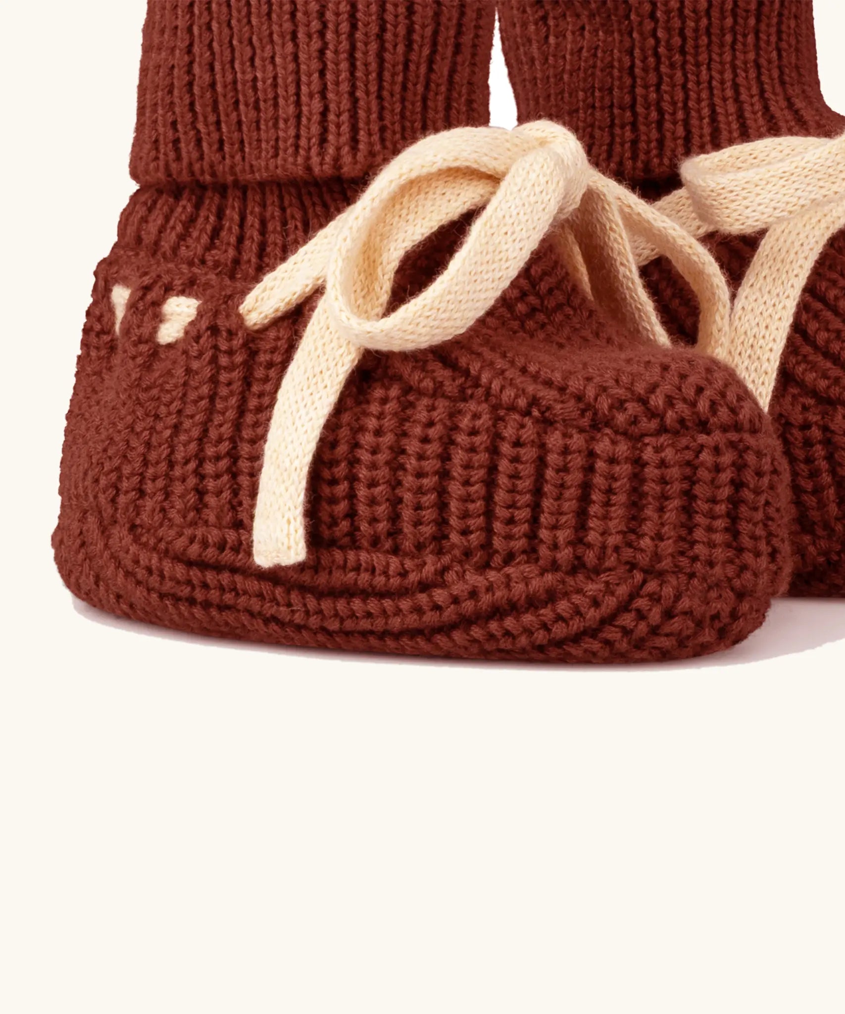 Close up of the Little Green Radicals hazelnut rust brown organic cotton knitted baby booties.