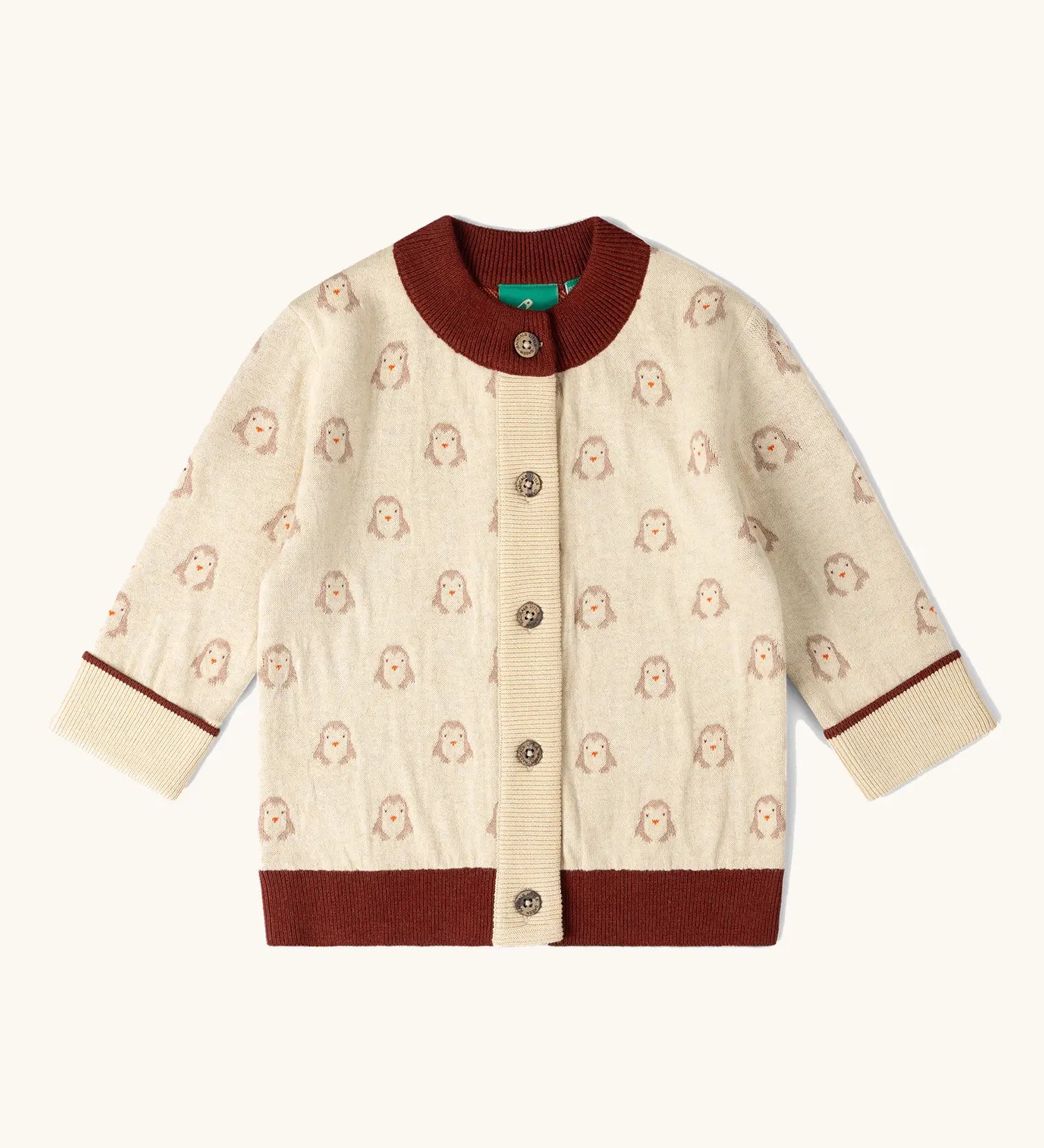 Little Green Radicals organic cotton knitted cardigan with snow penguins design. Natural cream cardigan with penguins all over, maroon trim on the collar and hem line.