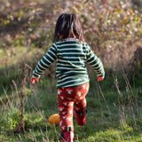 Child wearing the Little Green Radicals organic cotton knitted joggers with a mushroom design with red wellingtons and green striped long sleeved top.