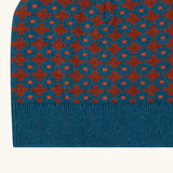 Close up of the Little Green Radicals organic cotton knitted kids beanie hat with a ginger squares design. Blue knitted hat with orange squares.