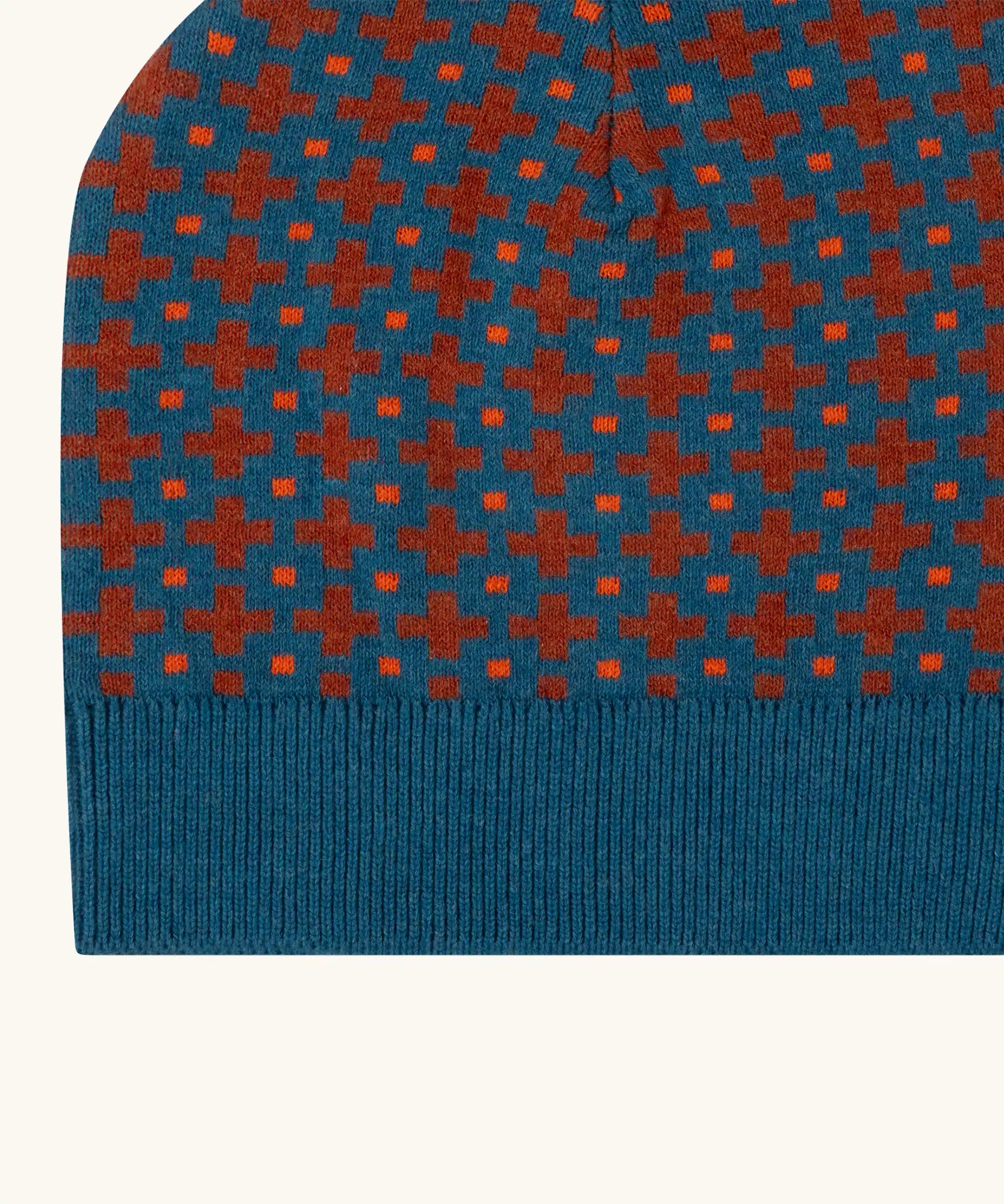 Close up of the Little Green Radicals organic cotton knitted kids beanie hat with a ginger squares design. Blue knitted hat with orange squares.