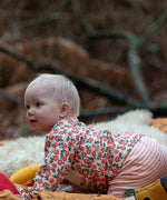 Baby wearing the Little Green Radicals organic cotton long sleeve top and jogger playset with pink petals flowers design.