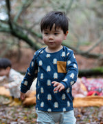Child wearing the Little green Radicals blue penguin design playset outfit. Long sleeved organic cotton top in navy with penguins all over and light blue and white striped joggers.