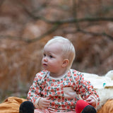 Baby wearing the Little Green Radicals organic cotton long sleeve top and jogger playset with pink petals flowers design.