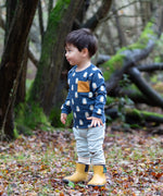Child wearing the Little green Radicals blue penguin design playset outfit. Long sleeved organic cotton top in navy with penguins all over and light blue and white striped joggers.