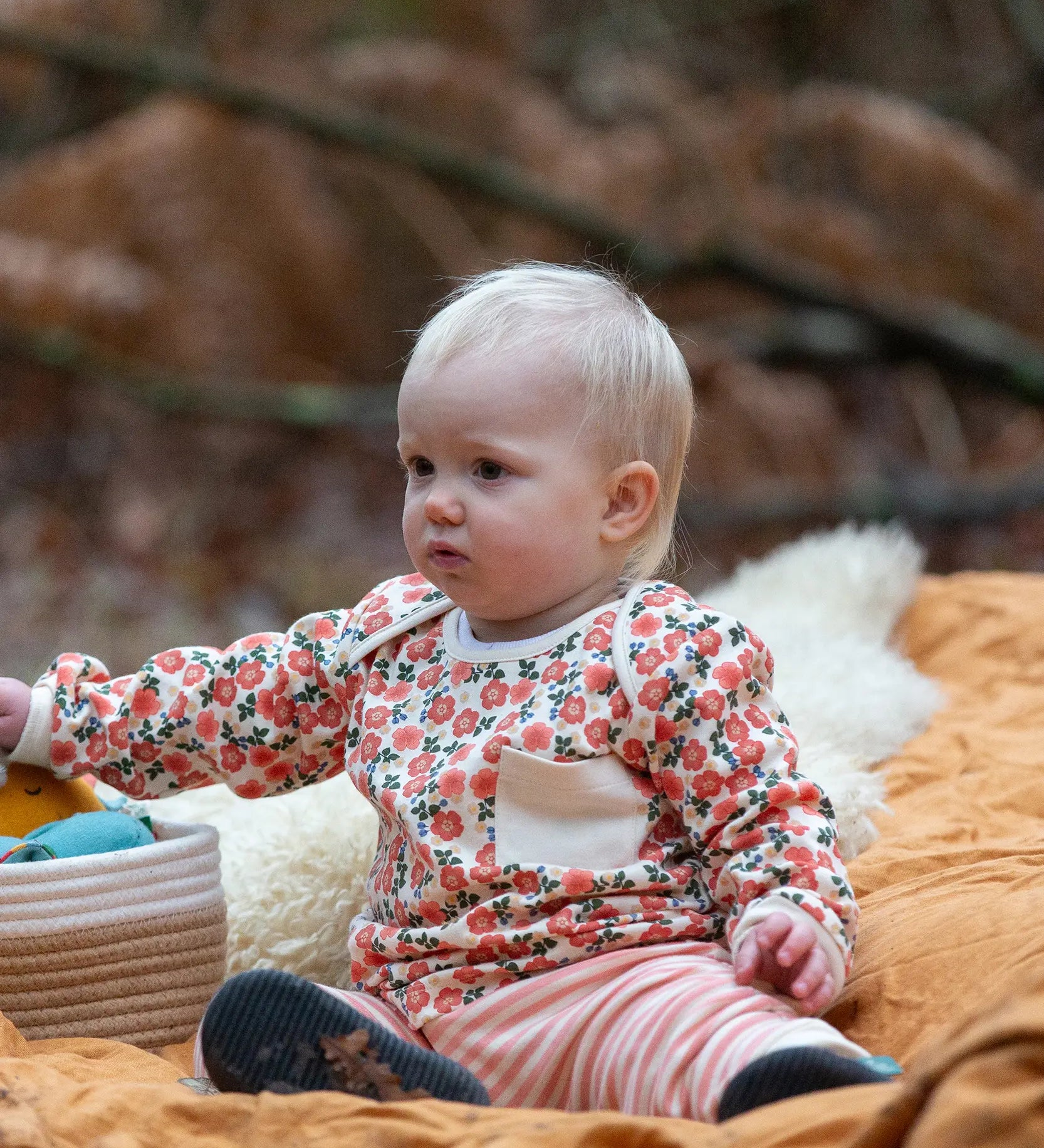 Baby wearing the Little Green Radicals organic cotton long sleeve top and jogger playset with pink petals flowers design.
