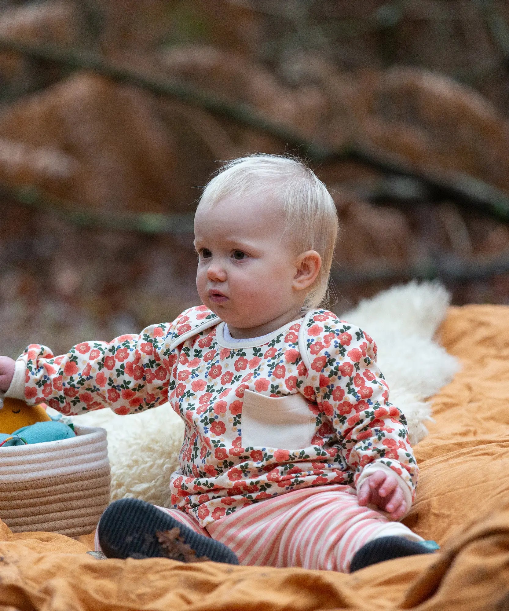 Baby wearing the Little Green Radicals organic cotton long sleeve top and jogger playset with pink petals flowers design.