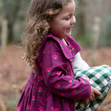 Child wearing the Little Green Radicals pink flowers sailor dress in purple with green wellington boots. 