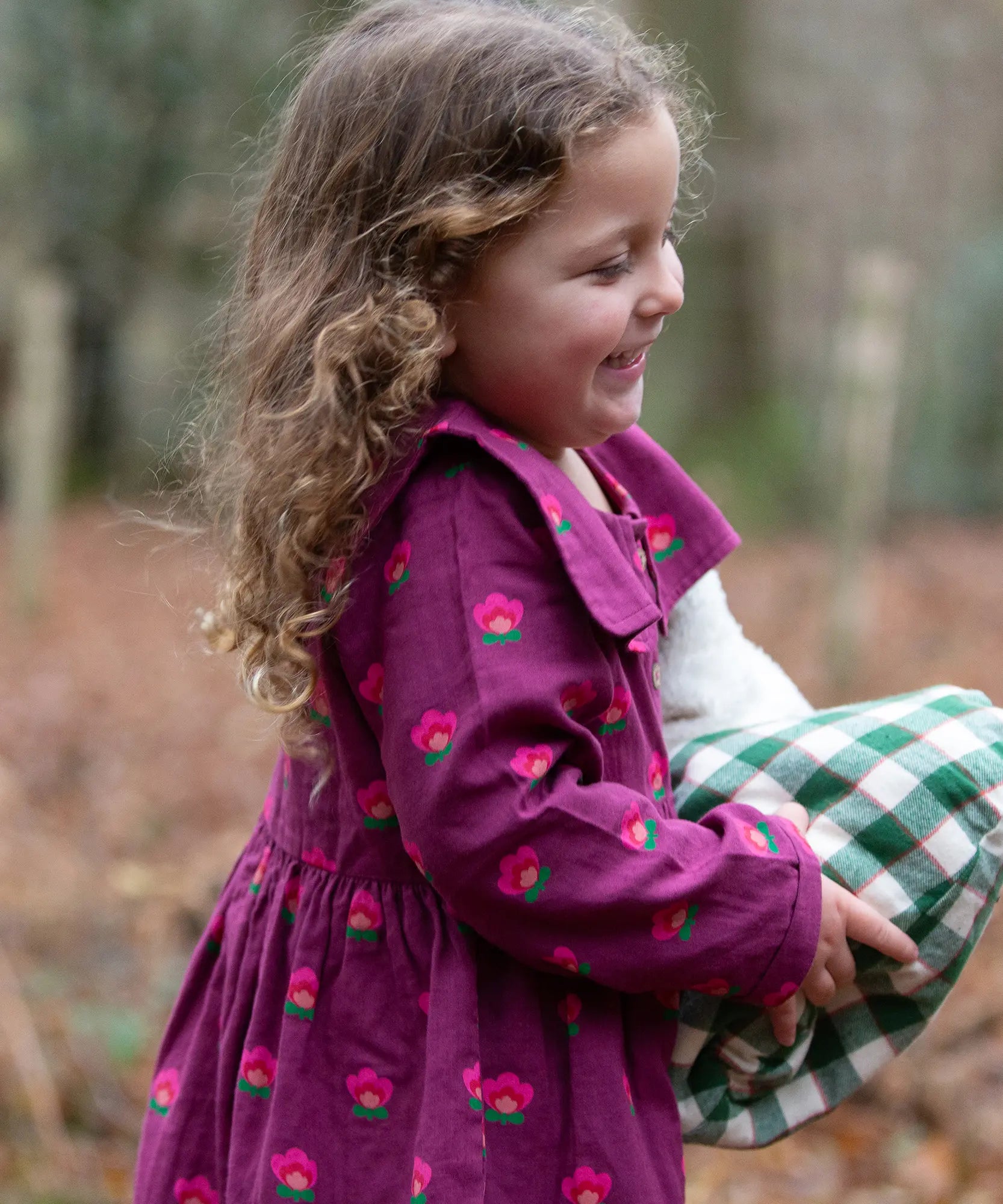 Child wearing the Little Green Radicals pink flowers sailor dress in purple with green wellington boots. 