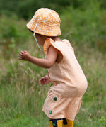  Little Green Radicals organic cotton reversible Flora sunhat with a yellow and white gingham design on a child. View of back.
