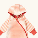 Close up of the top of the Little Green Radicals pink unicorns organic cotton reversible snug suit. One side is pink with a repeat unicorns print, the other is light pink and white striped. 