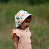 Child wearing the Little Green Radicals organic cotton reversible sunhat on the flora pink and yellow flowers print side.