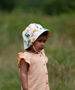 Child wearing the Little Green Radicals organic cotton reversible sunhat on the flora pink and yellow flowers print side.