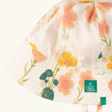 Close up of the Little Green Radicals organic cotton reversible Flora sunhat showing the repeat pink and yellow flower print .
