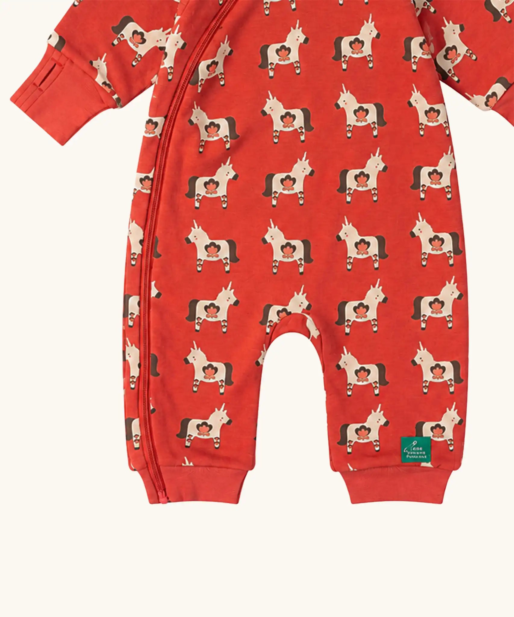 Close up of the front of the Little Green Radicals pink unicorns organic cotton reversible snug suit. One side is pink with a repeat unicorns print, the other is light pink and white striped. 