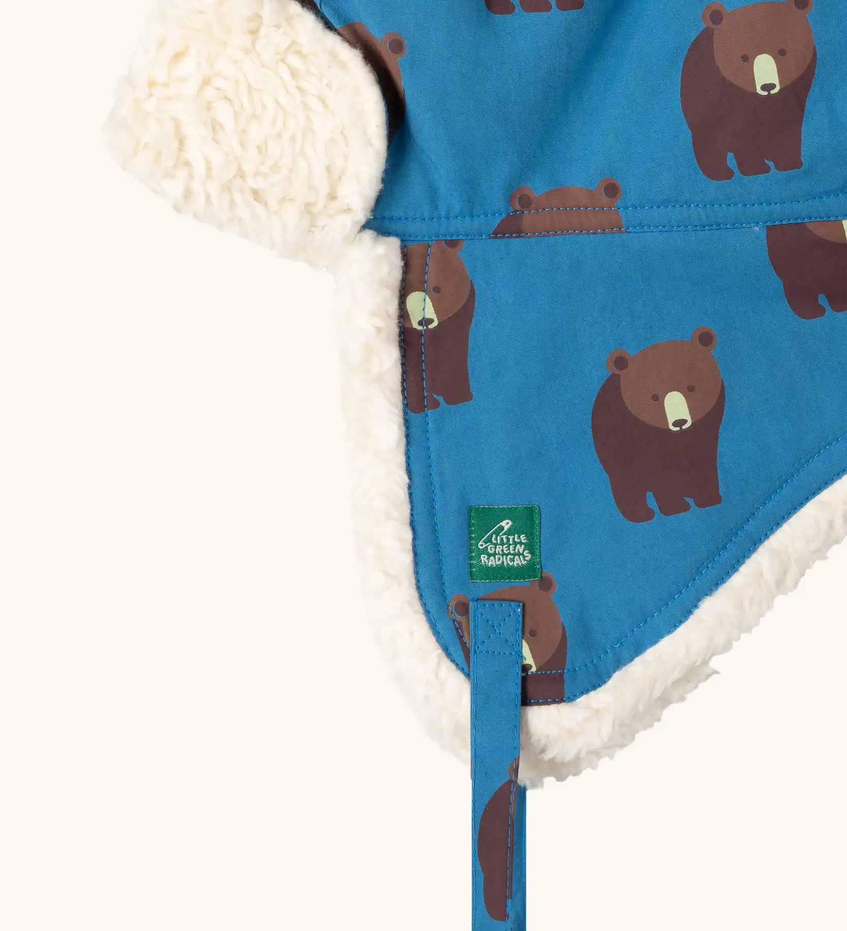 Close up of the Little Green Radicals organic cotton sherpa-lined trapper hat in blue with a bears print.
