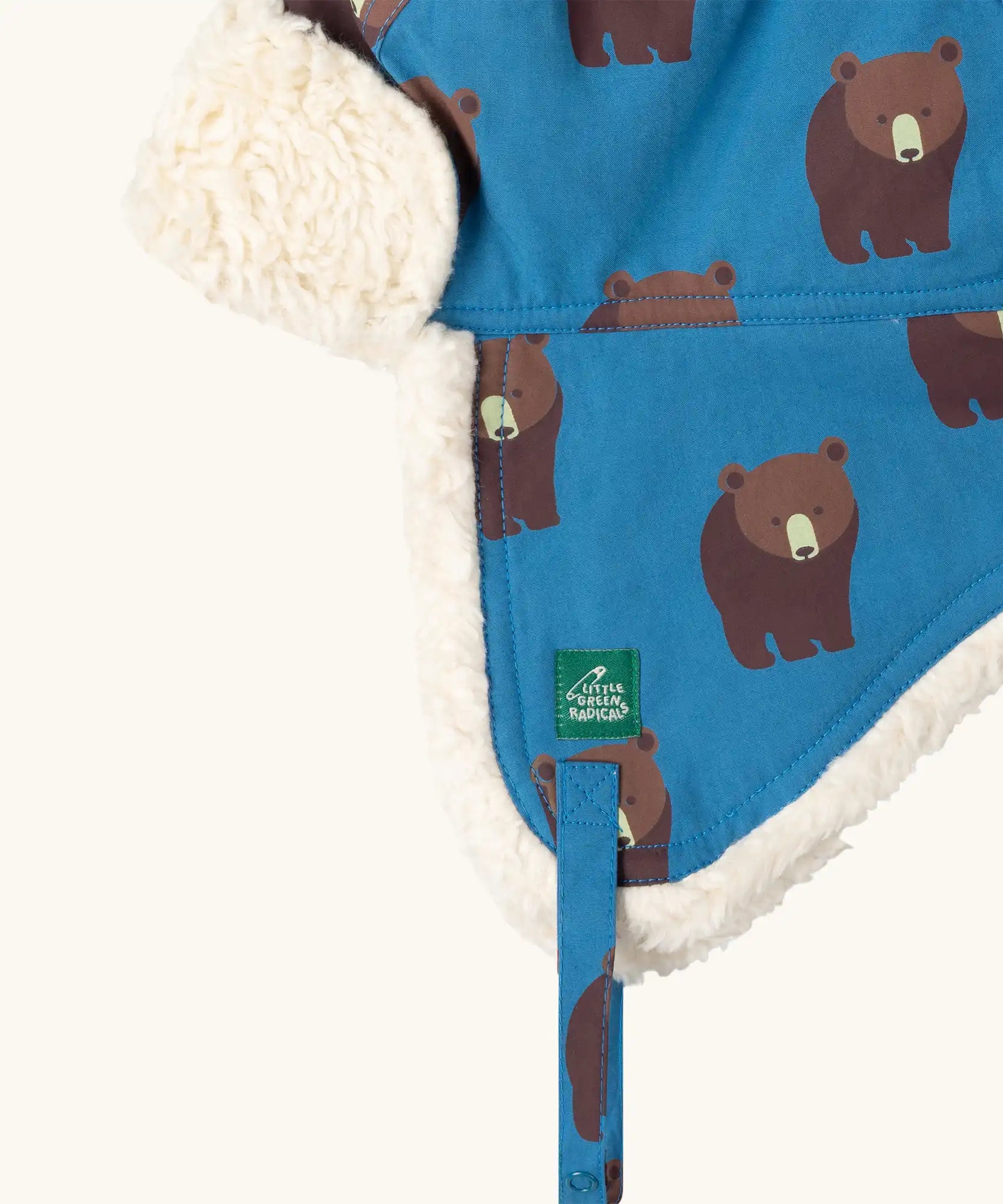 Close up of the Little Green Radicals organic cotton sherpa-lined trapper hat in blue with a bears print.