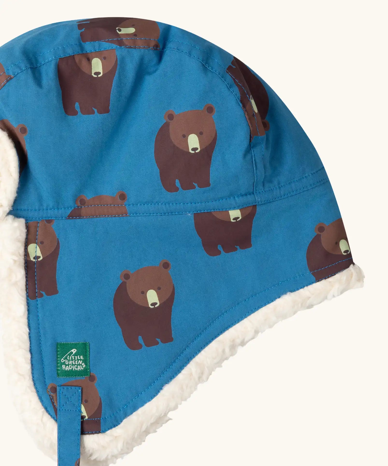 Close up of the Little Green Radicals organic cotton sherpa-lined trapper hat in blue with a bears print.