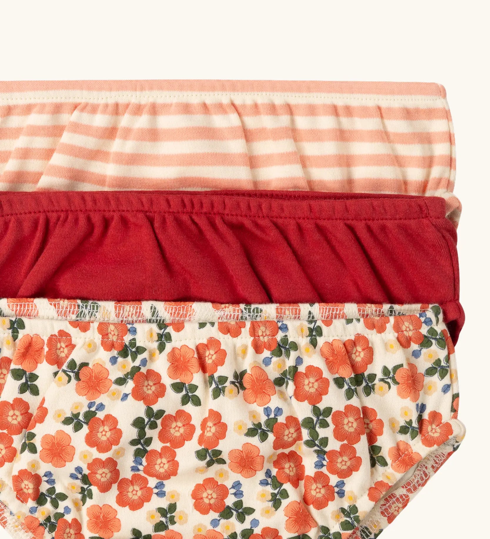 Close up of the elasticated waistbands on the Little Green Radicals organic cotton underwear in a 3 pack. Brief style pants one with a petals print, one red, one pink and white stripes. 