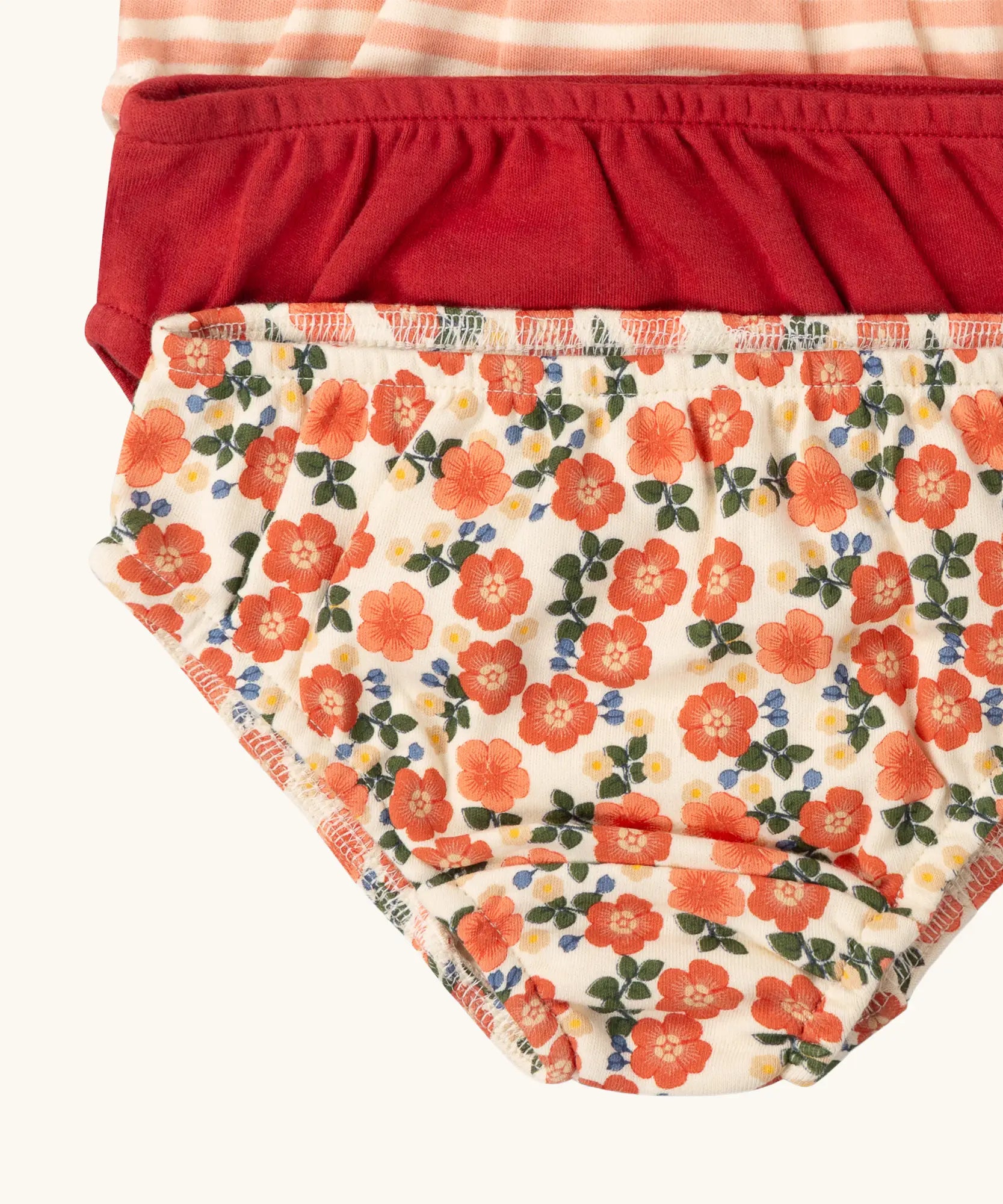 Close up of the elasticated leg hems on the Little Green Radicals organic cotton underwear in a 3 pack. Brief style pants one with a petals print, one red, one pink and white stripes. 
