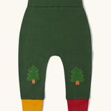 Little Green Radicals organic cotton woodland knee patch joggers. Dark green joggers with tree patches on the knee, one yellow and one red leg cuffs.