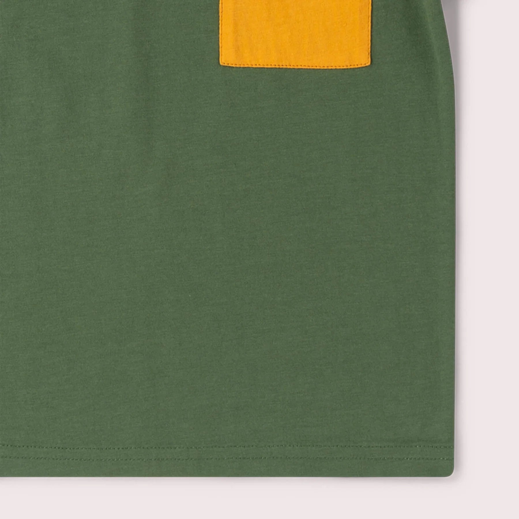 Closeup of Little Green Radicals Kids' Top in chive green, showing the organic cotton jersey fabric and hem stitching.