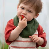 Child wearing the dark green bandana style bib from the Little Green Radicals blue moon organic cotton muslin bib set.