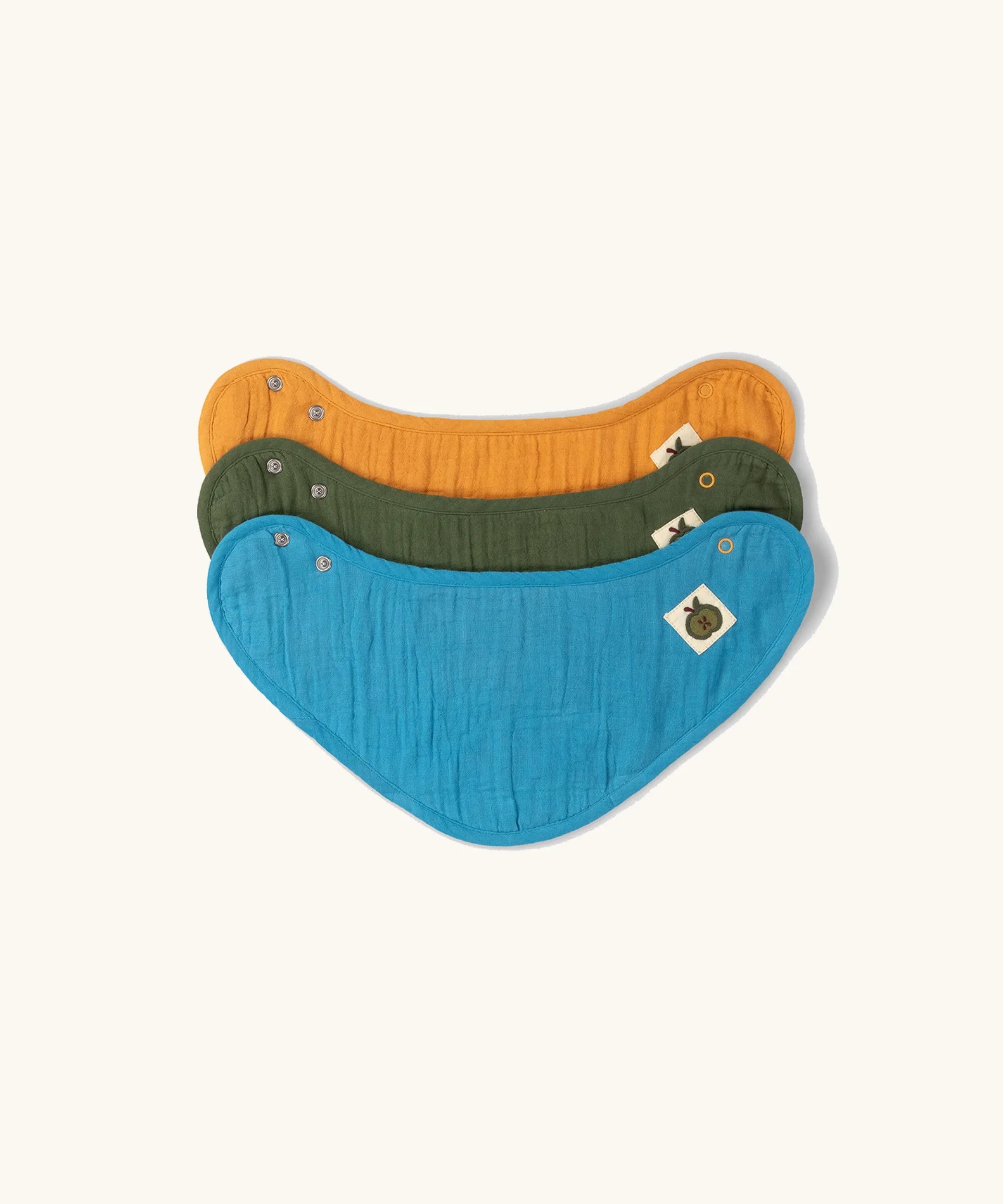 Little Green Radicals blue moon organic cotton muslin bandana bib set. Ochre yellow, dark green and teal blue bibs with green apple tag detail on one side.