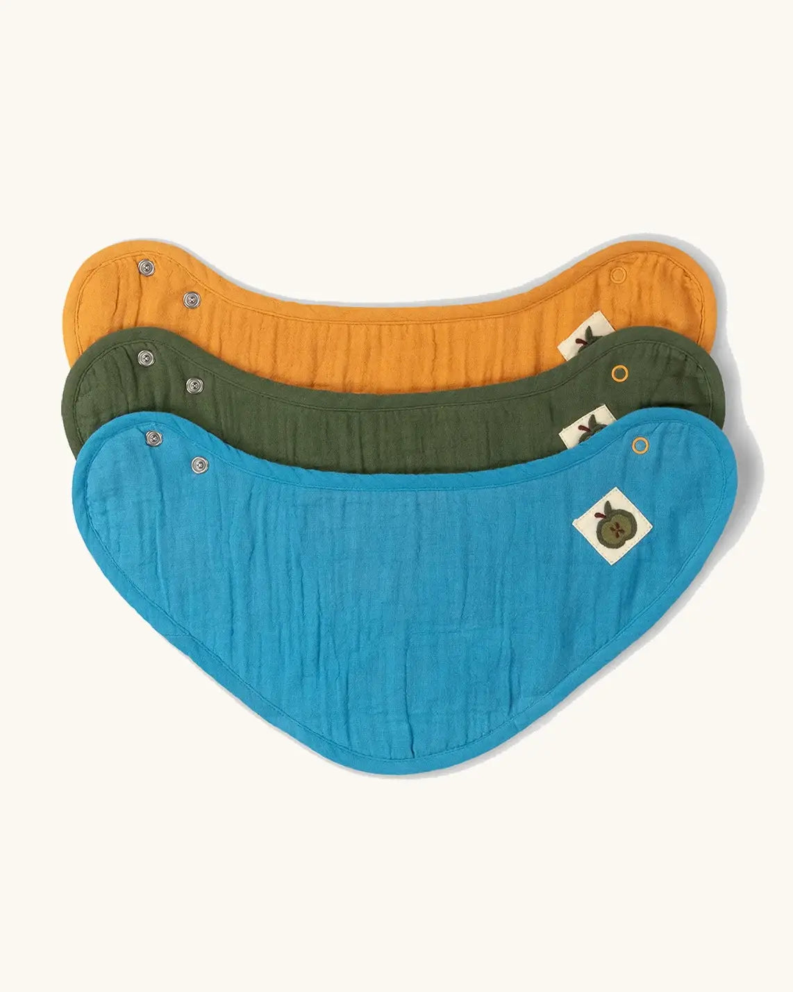 Little Green Radicals blue moon organic cotton muslin bandana bib set. Ochre yellow, dark green and teal blue bibs with green apple tag detail on one side.
