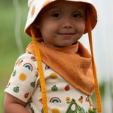 Child wearing the yellow ochre gold bandana style bib from the Little Green Radicals blue moon organic cotton muslin bib set.