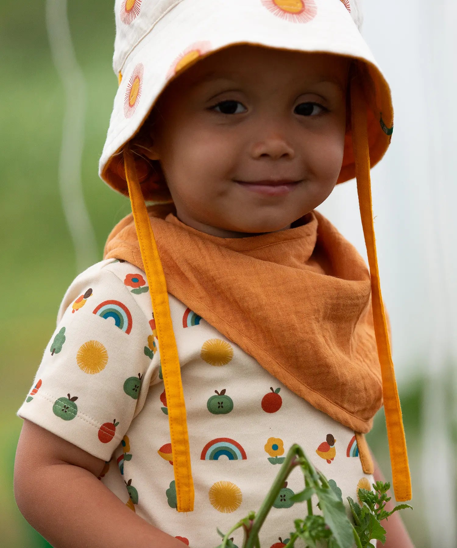 Child wearing the yellow ochre gold bandana style bib from the Little Green Radicals blue moon organic cotton muslin bib set.