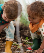 Child wearing the yellow ochre gold bandana style bib from the Little Green Radicals coral pink organic muslin bib set.