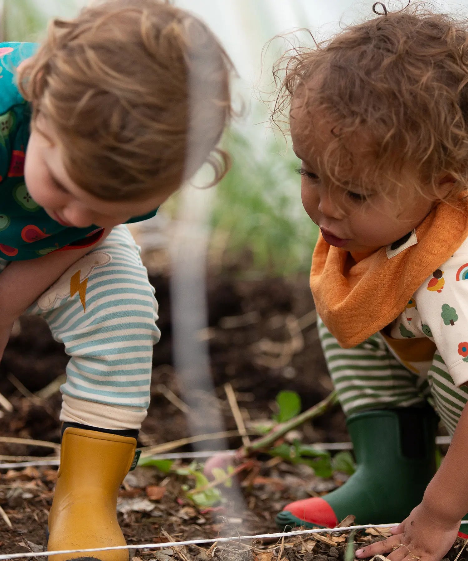 Child wearing the yellow ochre gold bandana style bib from the Little Green Radicals coral pink organic muslin bib set.