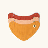 Little Green Radicals coral pink organic muslin bib set. Gold ochre yellow, red rust, and coral pink bandana style bibs in a pack of three.