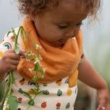 Child wearing the yellow ochre gold bandana style bib from the Little Green Radicals coral pink organic muslin bib set.