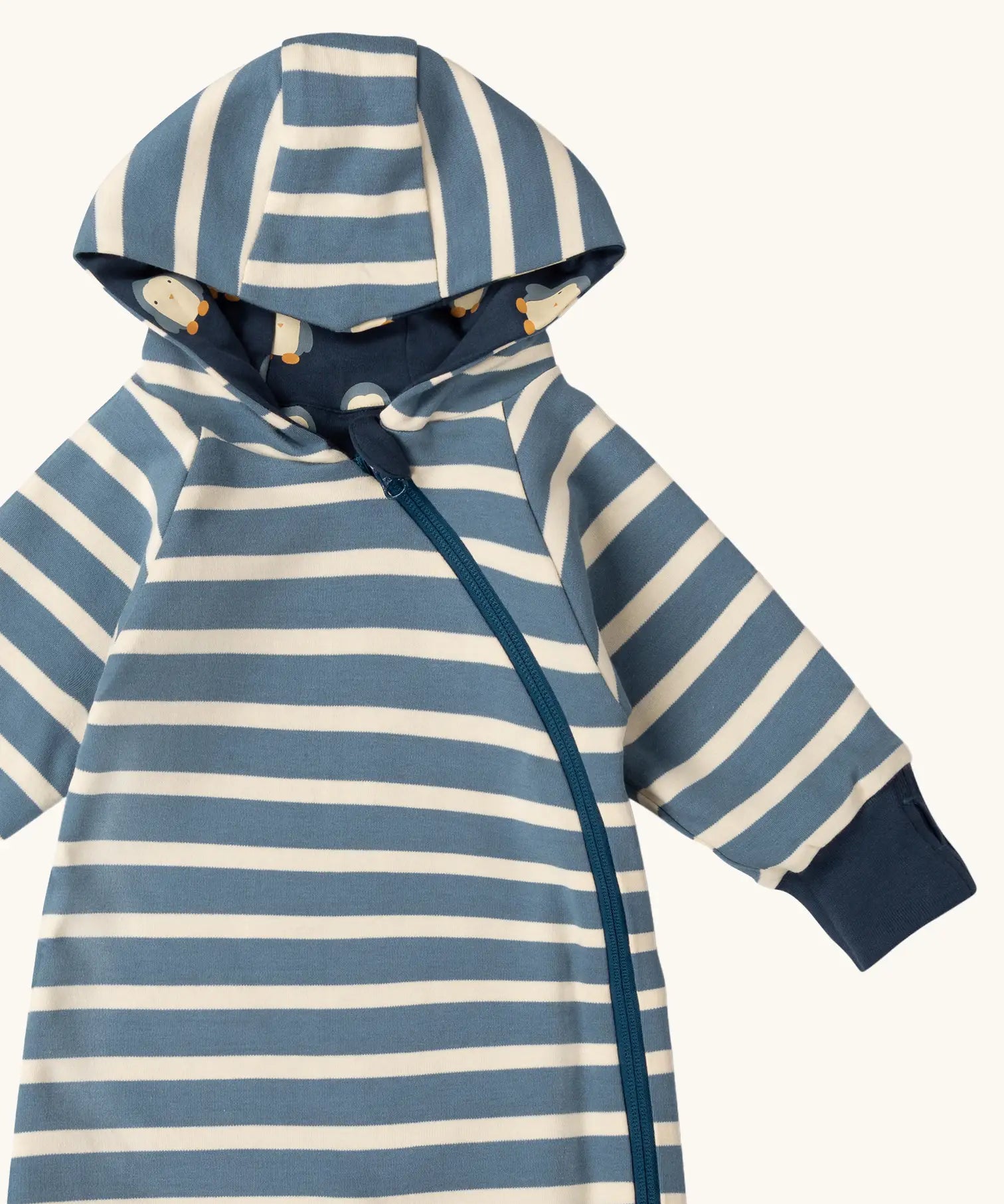 Close up of the Little Green Radicals navy blue penguins hooded reversible snug suit shown with the blue stripe design on the outdide.