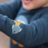 Close up of the fish embroidery detail on sleeve of the Little Green Radicals blue penguins applique long sleeve organic cotton top in navy.