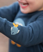 Close up of the fish embroidery detail on sleeve of the Little Green Radicals blue penguins applique long sleeve organic cotton top in navy.