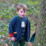 Child wearing the Little Green Radicals blue penguins applique long sleeve organic cotton top in navy with a midnight navy colour snuggly knitted cardigan and dark green joggers.