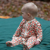 Baby wearing the Little Green Radicals petals GOTS organic cotton zip up babygrow. Natural coloured cotton with an all over pink flowers print.