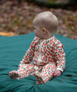 Baby wearing the Little Green Radicals petals GOTS organic cotton zip up babygrow. Natural coloured cotton with an all over pink flowers print.