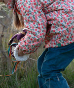 Close up of a child wearing Little Green Radicals pink petals recycled waterproof adventure Winter coat with blue corduroy trousers.