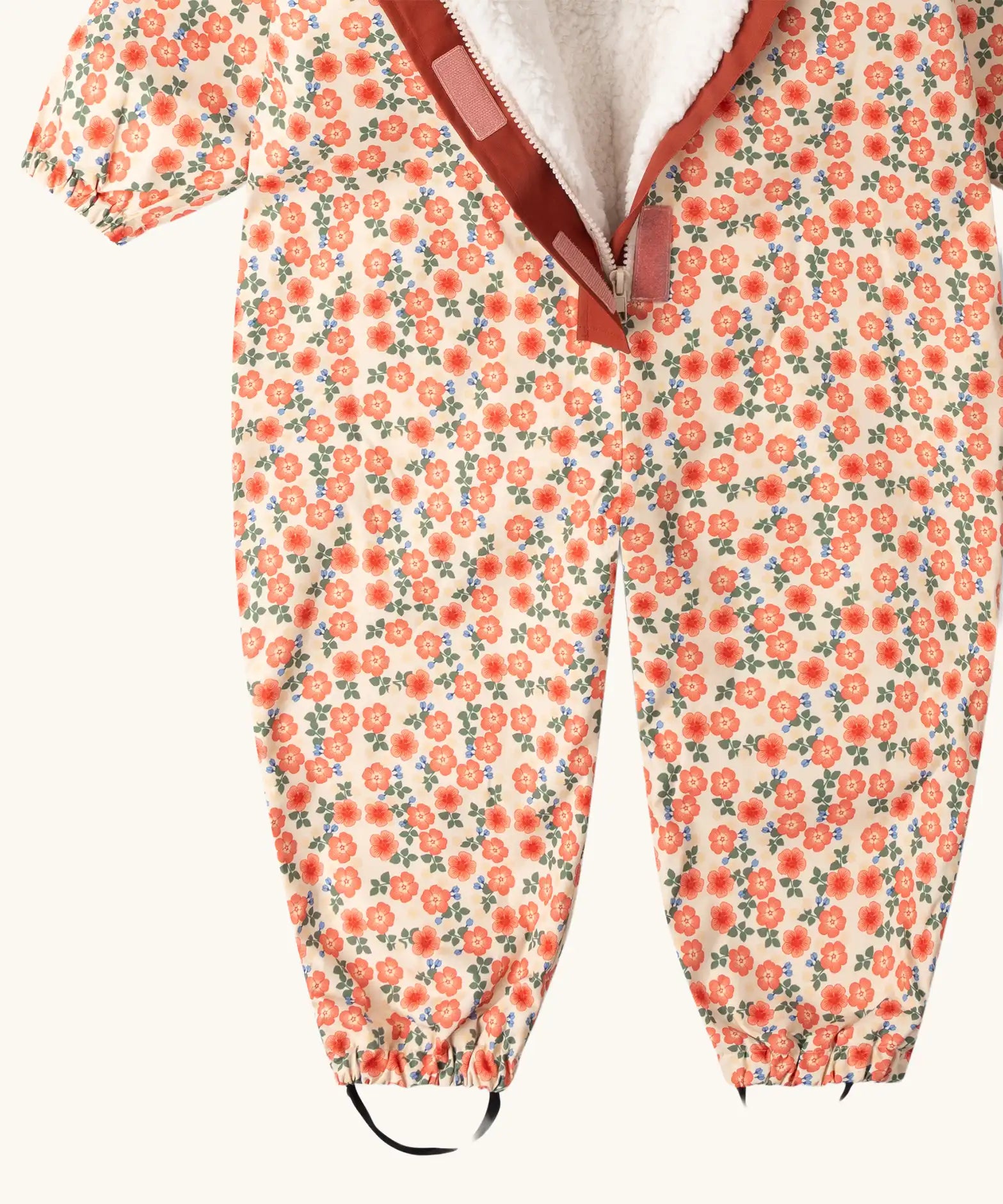 Close up of the boot straps on the Little Green Radicals petals recycled waterproof winter suit. Light background with pink repeat al over flower print. 
