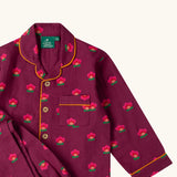 Close up of the Little Green Radicals pink flowers print organic cotton classic purple pyjamas. Long sleeve button up top with matching trousers.